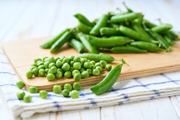 bundle of green peas on a white wooden table, selective focus.
