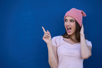 Young woman expressing surprise against blue background