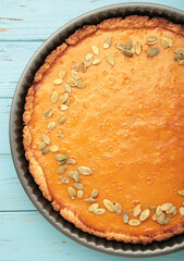 Delicious pumpkin pie on blue wooden background. Thanksgiving and fall-themed culinary concept.
