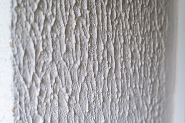 Close-up, background texture of a beige-white facade wall of a house made of decorative plaster. Abstract surface