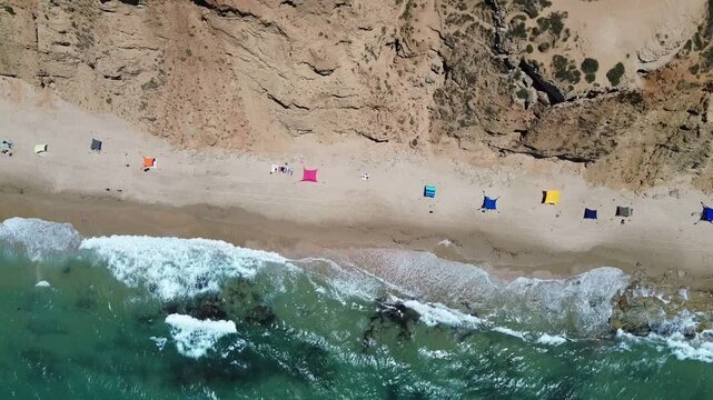 Flying over tents at wild Gaash natural reserve beach on the Mediterranean sea coast near Herzliya, Israel, aerial footage
