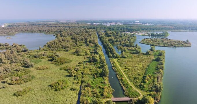 Aerial view of canal and lakes surrounded by lush green vegetation with trees and bushes, nature reserve Lepelaarplassen, Almere, Flevoland, Netherlands.