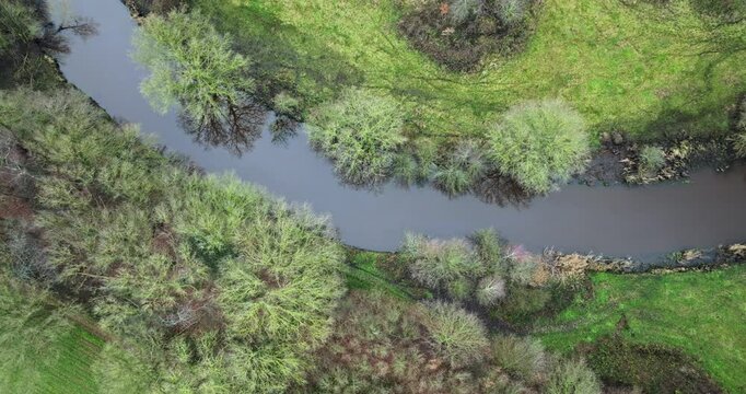 Aerial view of a tranquil river Midden Regge in vibrant landscape of green fields and lush trees, casting soft reflections, nature reserve De Tatums, Hellendoorn, Overijssel, Netherlands.