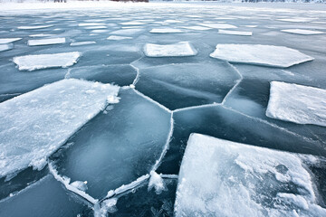 Icy surface with smooth texture and geometric shapes reflecting light in a winter landscape