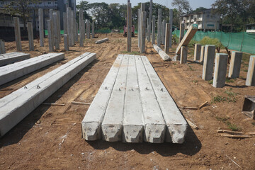 Prestressed concrete square piles are arranged in order to prepare for pile driving work at the building construction site. 