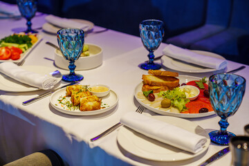 A festive table with cutlery and snacks in a dark room of the restaurant.
