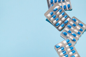 Health and medicine concept. White and blue capsules in silver blister pack on blue background top view. Tablets, pills, vitamins, food supplements, probiotic. Pharmacology, health and beauty care