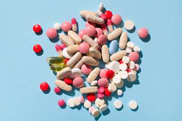 Different multi-colored tablets, vitamins, pills on blue background close-up. Concept of health and...