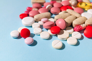 Different multi-colored tablets, vitamins, pills on blue background close-up. Concept of health and medicine, healthcare and pharmacology. Dietary supplements and homeopathy background