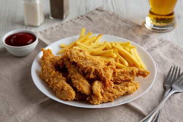 Homemade Chicken Strips with Fries on a Plate, side view.