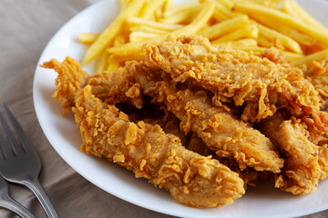 Homemade Chicken Strips with Fries on a Plate, low angle view. Close-up.