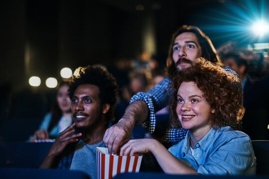 Young diverse group of friends watching a movie together in the movie theater