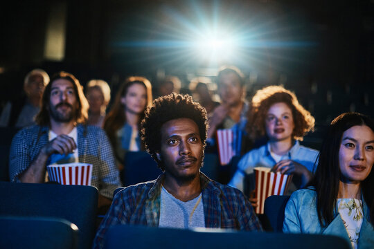 Young diverse group of friends watching a movie together in the movie theater