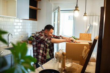 Man unpacking moving boxes while settling into new kitchen