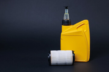 Motor oil in plastic canister and filter on dark grey background, space for text