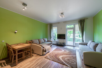Bright Modern Living Room With Green Accents and Large Windows Opening to Nature