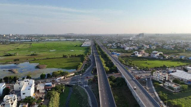 Aerial view of Chennai highway interchange elevated roads, busy traffic, and a mix of residential areas and green spaces. urban infra. flow of traffic and life in a developing Indian metropolis.
