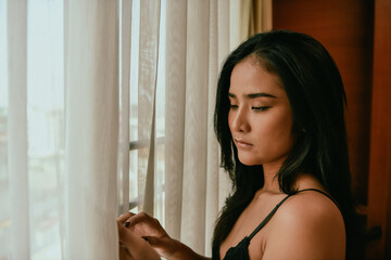 A contemplative woman gazing out the window, creating a serene atmosphere of reflection and...