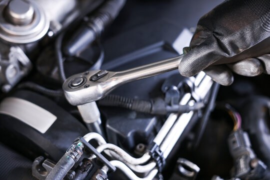 Auto parts. Professional mechanic with torque wrench fixing car indoors, closeup