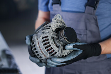 Auto part. Professional mechanic with alternator near indoors, closeup. Space for text