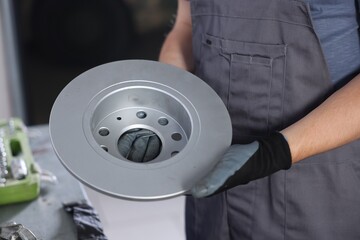 Auto parts. Professional mechanic with brake disc indoors, closeup