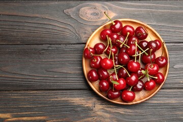 Fresh ripe cherries on black wooden table, top view. Space for text