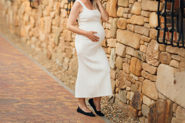 without a face. Pregnant woman in white running dress on a walk.