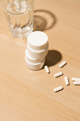 Mockup of dietary supplements or vitamins in a white plastic bottle with a blank label, placed next...