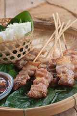 Thai style grilled pork and steamed sticky rice With Jaew dipping sauce on a wooden floor