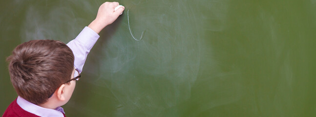 boy writes chalk on blackboard