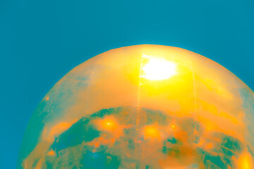A vibrant, abstract artwork featuring a close-up of a shiny, surface reflecting multicolored light. The dominant hues are red, orange, yellow, and pink, with hints of blue and green.