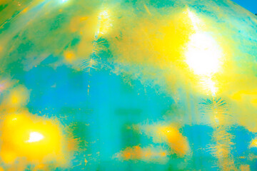 A vibrant, abstract artwork featuring a close-up of a shiny, surface reflecting multicolored light. The dominant hues are red, orange, yellow, and pink, with hints of blue and green.