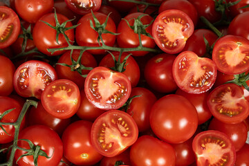 Juicy vegetable tomato background, lots of tomatoes whole and cut in half top view.
