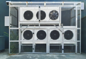 View from the street of large white industrial air conditioners with gray protective mesh. Concept...