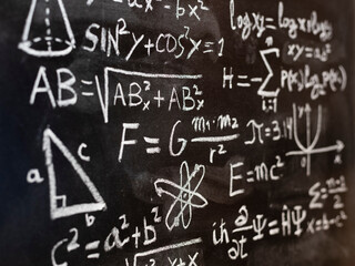 Operaciones y formulas de física cuántica y matemáticas escritas a mano con una tiza en la...