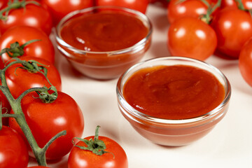 Glass Bowls of Ketchup Surrounded by Fresh Tomatoes. Homemade Sauce Concept.
