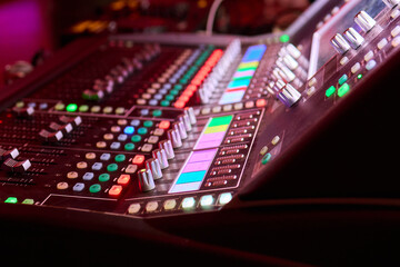Closeup image of a hand mixing sounds on a control board, showcasing an audio technicians work