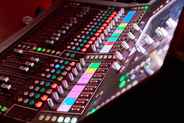 Closeup image of a hand mixing sounds on a control board, showcasing an audio technicians work