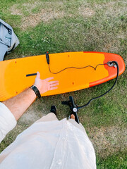 Preparing for a paddleboarding adventure on a vibrant orange board in a grassy area