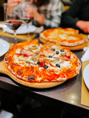 Enjoying delicious pizzas with friends at an Italian restaurant in the evening