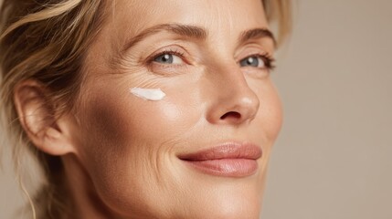 A beautiful woman with cream on her face looks directly at the camera and smiles