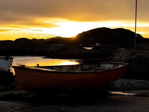 Sunset over a rocky harbor with fishing boats.