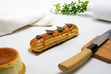 caramel glazed eclair with chocolate decors on elegant white table setting