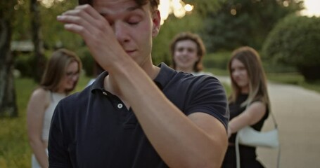 A diverse group of young friends shares laughter and genuine smiles while walking through a beautiful park at sunset. Capturing moments of happiness, connection, and carefree summer vibes.