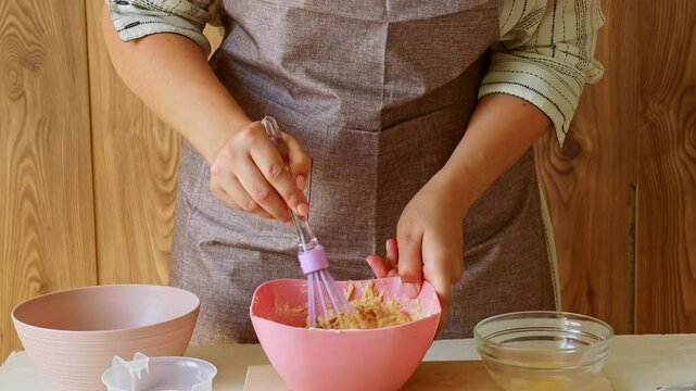 Female hands mixing batter in a bowl to prepare dough for muffins and cookies