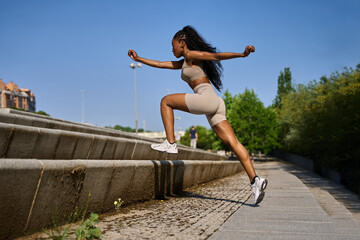 Young sporty woman jumping on stairs in a city park