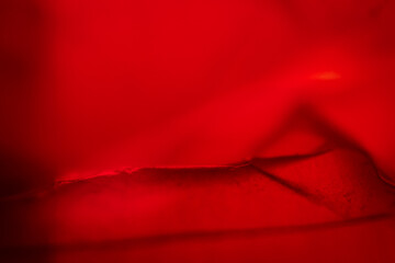 Extreme close up of red empty plastic bag background. The plastic surface is wrinkly and tattered making abstract pattern. Selective focus, shallow depth of field.
