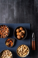 Bowls with nuts and blue table cloth on black chalkboard background. Flat lay. Top view.