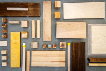Flat lay of various wood and plywood pieces on concrete texture. Carpentry background.