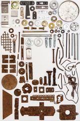 A group of various old and new bits and pieces arranged on white. Old rusty nuts, bolts, nails and other parts flay lay on white background.